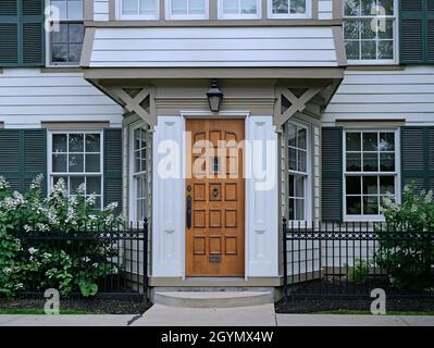 Wood grain front door of old fashioned white clapboard house with shutters Stock Photo