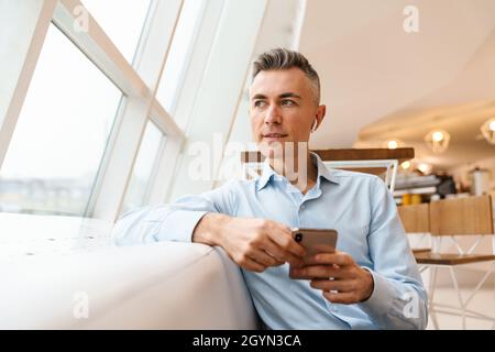 Confident handsome businessman using smartphone in cafe indoors Stock Photo