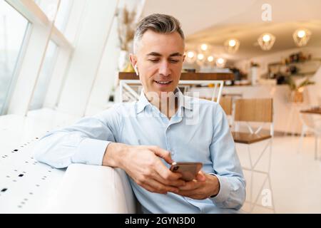 Confident handsome businessman using smartphone in cafe indoors Stock Photo