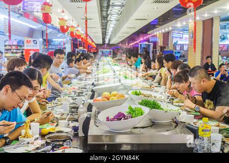 Beijing China,Guanganmen Outer Street,Rainbow Center Asian man male woman female couple,eating restaurant dining food conveyor belt Kaiten-zushi sushi Stock Photo