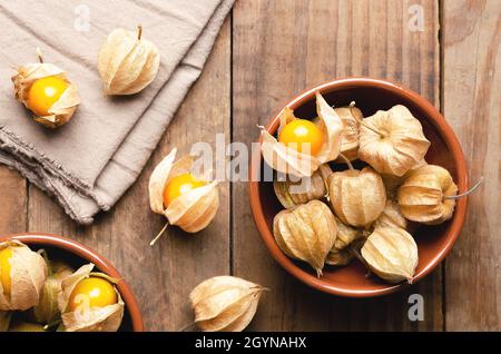 Physalis Peruvian fruits in brown bowls on a wooden background. Stock Photo