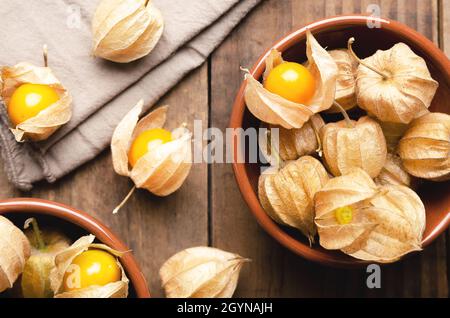 Physalis Peruvian fruits in brown bowls on a wooden background. Stock Photo