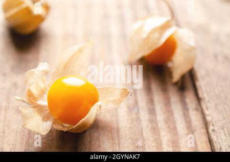Three physalis Peruvian fruits on a wooden background. Stock Photo