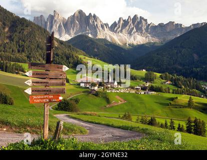evening panoramic view of Geislergruppe or Gruppo dele Odle from Saint Magdalena with tourist sign post, Italian Dolomites Alps mountains Stock Photo