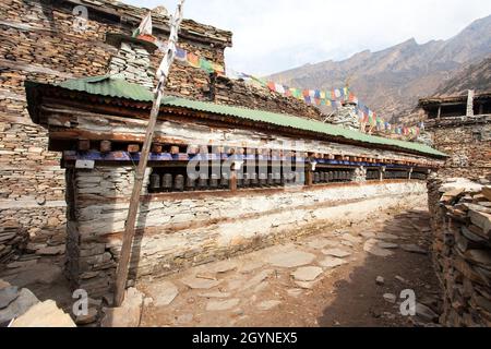 Buddhist prayer many wall with prayer wheels in nepalese village, round Annapurna circuit trekking trail, Nepal Stock Photo