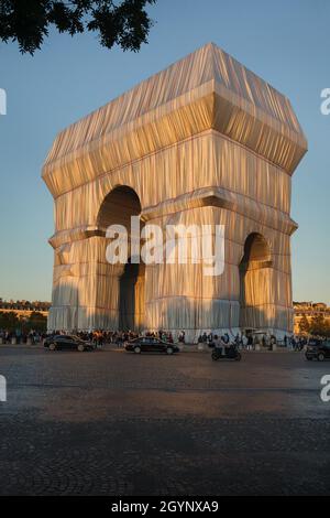 The Arc de Triomphe wrapped in silver-blue fabric fastened with red ropes in the Place Charles de Gaulle in Paris, France. The Arc de Triomphe was wrapped for two weeks being converted to an artwork as it was designed by Christo and Jeanne-Claude in September 2021. Stock Photo