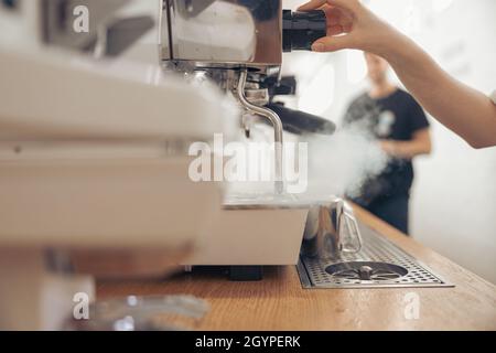 Female barista using coffee machine in cafeteria Stock Photo