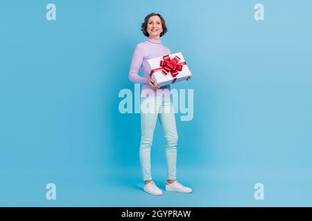 Full length profile side photo of elderly woman happy positive smile hold present box birthday isolated over blue color background Stock Photo