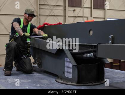 Jessie Mauldin, 673d Logistics Readiness Squadron heavy mobile equipment mechanic, unscrews a bolt in order to attach an eyelet on top of a deicing truck to tether a fall-protection safety harness at Joint Base Elmendorf-Richardson, Alaska, Jan. 22, 2019. The modification involves strategically attaching four eyelets to the top of each truck so mechanics can attach a mobile safety harness. Mauldin has taken steps to push his innovation to all heavy mobile equipment maintenance shops Air Force-wide. Stock Photo