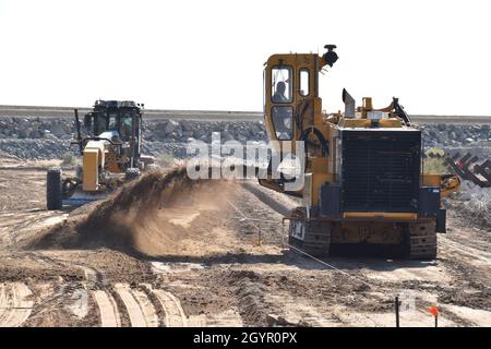 A scraper smoothes soil while a trencher digs a deep channel for formwork and bollards to be placed near Yuma, Arizona, January 22, 2020. The U.S. Army Corps of Engineers, South Pacific Border District is providing contracting services, including design and construction oversight, of Department of Defense-funded Southwest border barrier projects in California, Arizona, New Mexico and Texas at the direction of the Administration and at the request of Department of Homeland Security, Customs and Border Protection (Some personal and corporate identifiable markings have been masked for privacy rea Stock Photo