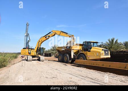 An excavator places a giant boulder into a dump truck to make way for sheet piling for barrier construction, near Yuma, Arizona, January 22, 2020. The U.S. Army Corps of Engineers, South Pacific Border District is providing contracting services, including design and construction oversight, of Department of Defense-funded Southwest border barrier projects in California, Arizona, New Mexico and Texas at the direction of the Administration and at the request of Department of Homeland Security, Customs and Border Protection (Some personal and corporate identifiable markings have been masked for pr Stock Photo