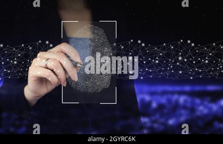 Password control through fingerprints. Hand holding digital graphic pen and drawing digital hologram fingerprint sign on city dark blurred background. Stock Photo