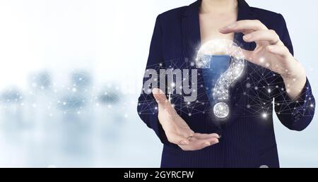 FAQ frequently asked questions concept. Two hand holding virtual holographic question mark icon with light blurred background. Business support concep Stock Photo