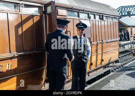 Sheringham, Norfolk, UK - SEPTEMBER 14 2019: Men in vintage train conductor uniforms stands by a vintage passenger carriage during 1940s weekend Stock Photo