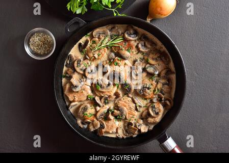 Pork medallions with mushroom gravy in cast iron pan over dark stone background. Top view, flat lay Stock Photo