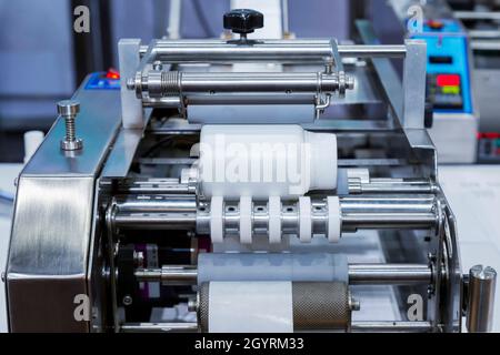White plastic bottle on small tabletop bottle sticker labeling machine for medicine and pharmaceutical industry. Stock Photo