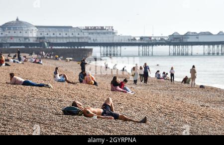 Brighton UK 9th October 2021 - Brighton beach is busy as visitors enjoy a hot sunny day with some parts of the South East forecast to reach over 20 degrees centigrade : Credit Simon Dack / Alamy Live News