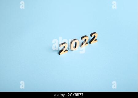 Studio shot with soft shadows falling on a blue surface of wooden numerals, symbolizing the New 2022 Year on colored background with copy space for te Stock Photo