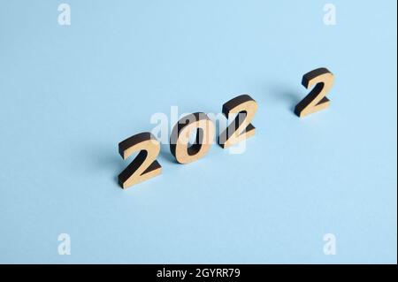 Studio shot with soft shadows falling on a blue surface of wooden numerals, symbolizing the New 2022 Year on colored background with copy space for te Stock Photo