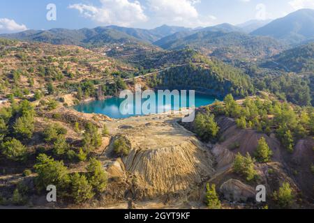 Abandoned pyrite mine in Xyliatos, Cyprus. Lake in open mine pit and waste heaps over mountains landscape Stock Photo