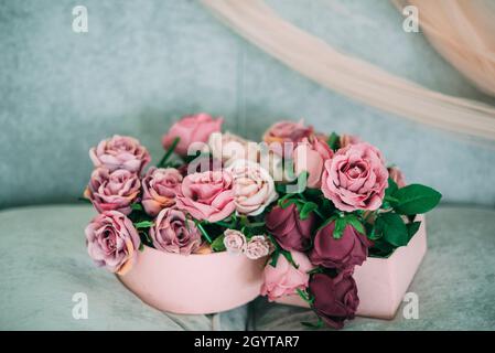 purple pink violet lilac beige rose flowers in boxes on the sofa Stock Photo