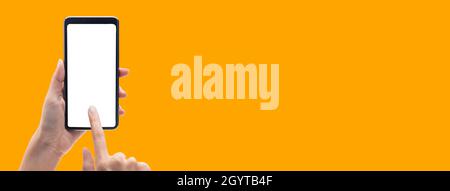 Hand holding the black smartphone and touching blank screen on colorful orange banner background, Clipping path. Stock Photo