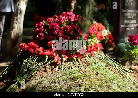 Flowers on the grave. Funeral ceremony. Flowers lie on the ground. Filled grave. Stock Photo