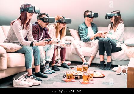 Friends playing with vr headset at home - Virtual reality and wearable tech concept with people having fun on 3d videogames - Generation z digital tre Stock Photo