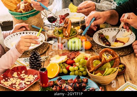 Hands of family dining withpicking food with fork on dining table. Sliced meat, fresh fruits with bread placed on table. Fresh cooked food and harvest Stock Photo