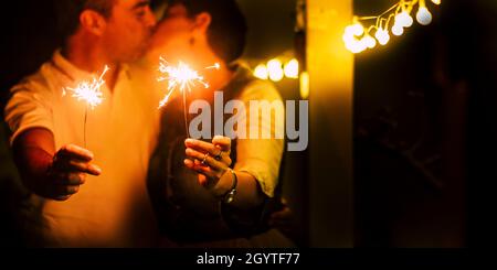 Couple holding burning sparkle, loving and kissing each other, celebrationg birthday, anniversary or new year. Affectionate couple kissing and holding Stock Photo