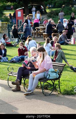 Cheltenham Literature Festival, Cheltenham, UK - Saturday 9th October 2021 - Festival goers enjoy the late afternoon sun whilst they read in the Festival Gardens - the Festival runs until Sunday 17th October - book sales have soared during the pandemic. Photo Steven May / Alamy Live News Stock Photo