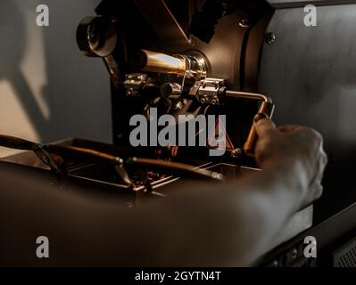Male worker using industrial coffee roasting machine at factory Stock Photo