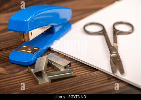 Office stapler, stapler staples and white paper on the table, close-up, selective focus Stock Photo