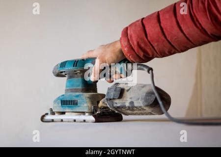 Man sanding wood plank using electric sand machine. Stock Photo