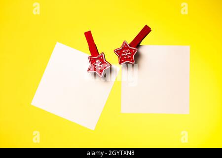Two sheets of white paper pinned with a Christmas clothespin yellow background, a place to copy Stock Photo