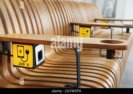 A socket with a device charging sign on a wooden bench at the airport. USB, Wireless, plug Stock Photo