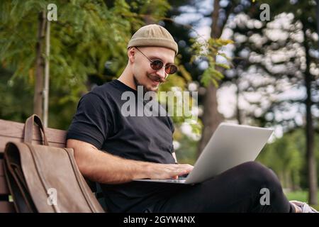 Stylish bearded student chatting working e-learning laptop ps at green park Millennial Hipster  Stock Photo