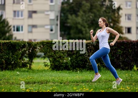 Graceful woman 29 years old in sportswear runs outdoors. Stock Photo