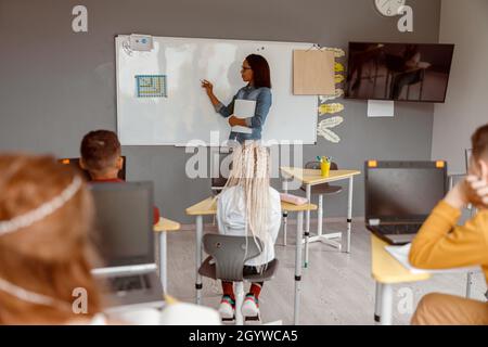Female teacher teaching kids in classroom at school Stock Photo