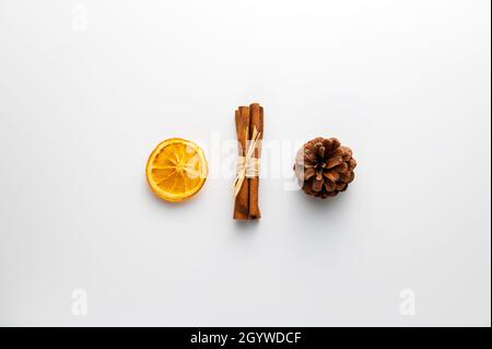 Christmas for three: a pine cone, a bunch of cinnamon sticks and a slice of dried orange in a row. Stock Photo