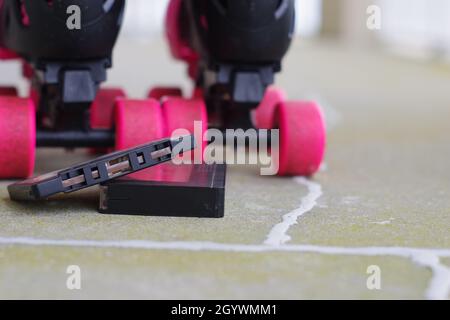 A pair of roller skates with pink wheels along with two vintage cassette tapes Stock Photo