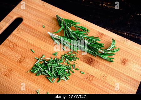 Chopped Rosemary on a Bamboo Cutting Board: Minced rosemary leaves on a wooden cutting board Stock Photo