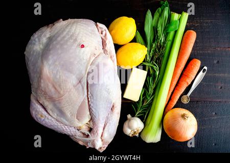 Roast Turkey Ingredients on a Dark Wood Background: Whole turkey, butter, and aromatics on a wooden table Stock Photo