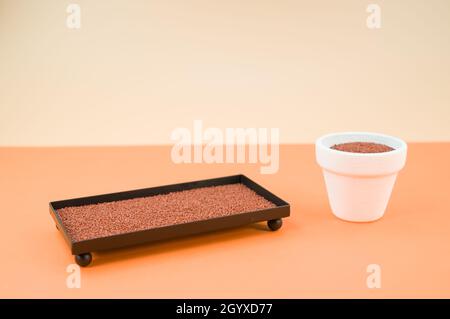 The terracotta containers filled with decorative sand isolated on orange background Stock Photo
