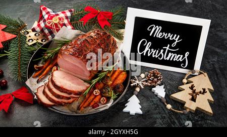 Christmas composition with baked ham on dark background. Traditional food concept. Stock Photo