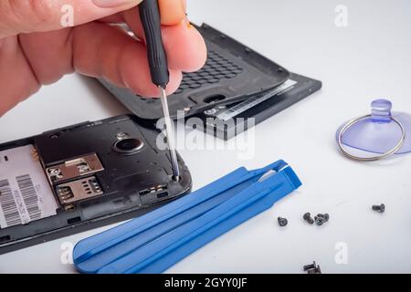 the master repairs a broken smartphone with the help of tools. Stock Photo