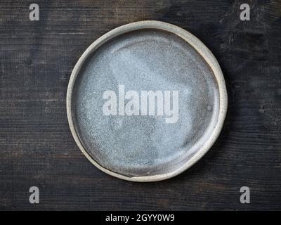 empty grey ceramic plate on dark wooden kitchen table, top view Stock Photo