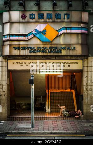 A homeless man sleeping at the entrance to Link Alley Shopping Arcade in the now-renovated Central Market, Central, Hong Kong Island, 2009 Stock Photo