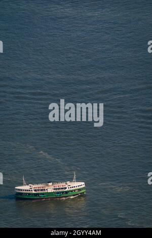 A Star Ferry crosses Victoria Harbour from Tsim Sha Tsui, Kowloon, to Hong Kong Island, seen from Level 106 of the ICC in West Kowloon, Hong Kong Stock Photo
