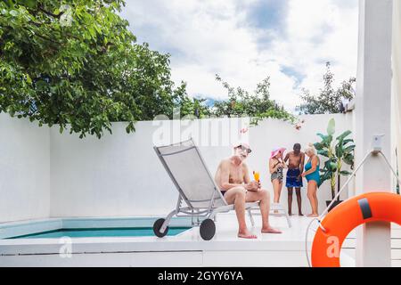 Happy seniors having party in the swimming pool - Elderly friends at a pool party Stock Photo